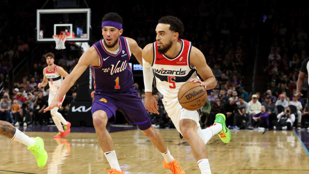 Washington Wizards guard Tyus Jones (5) drives to the net against Phoenix Suns guard Devin Booker (1) during the first quarter at Footprint Center. 